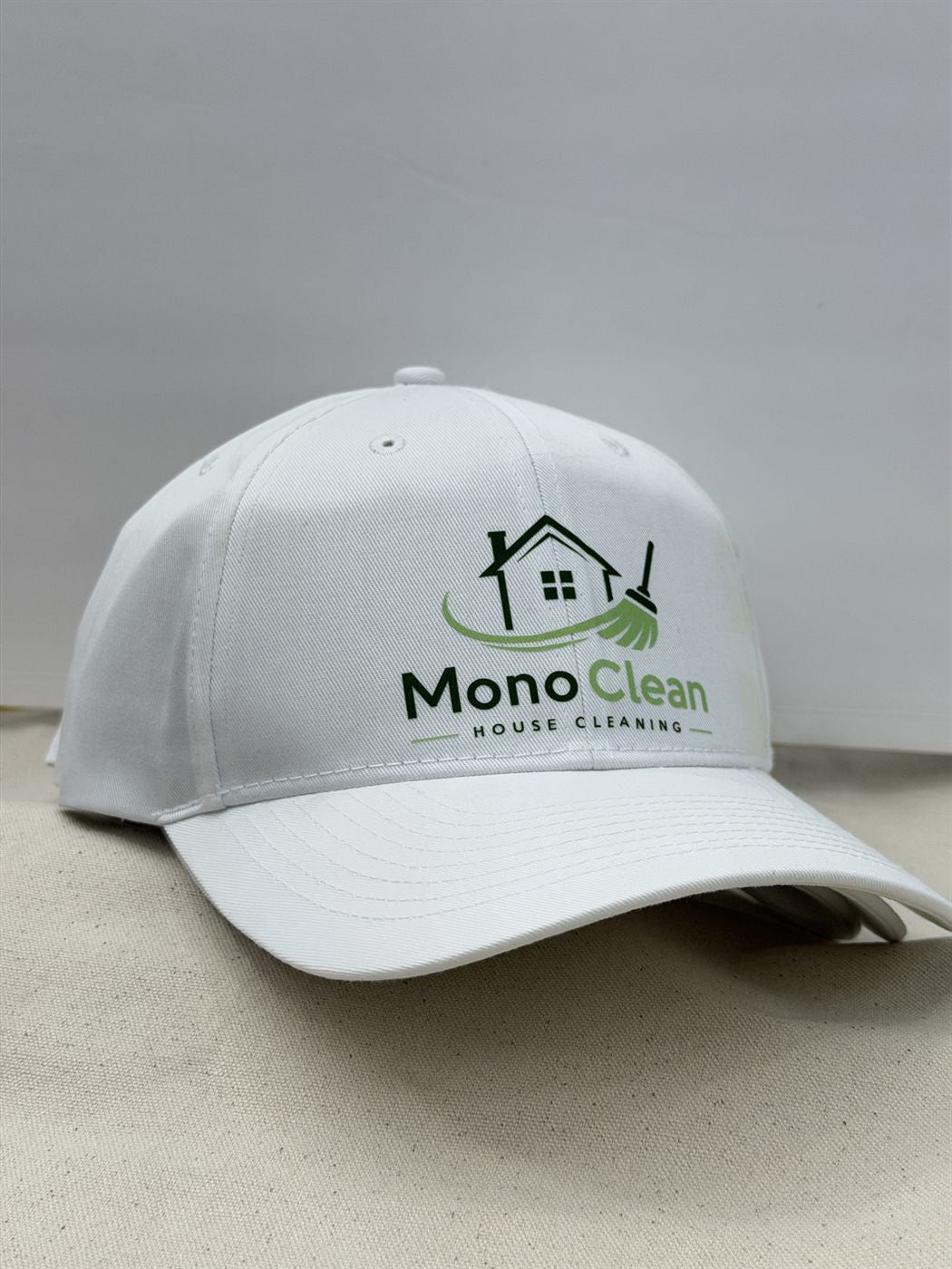 White cap with embroidered cleaning company logo